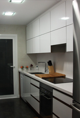 Cocina de madera laminada con encimera de Silestone y tirador uñero realizada a medida en Barcelona